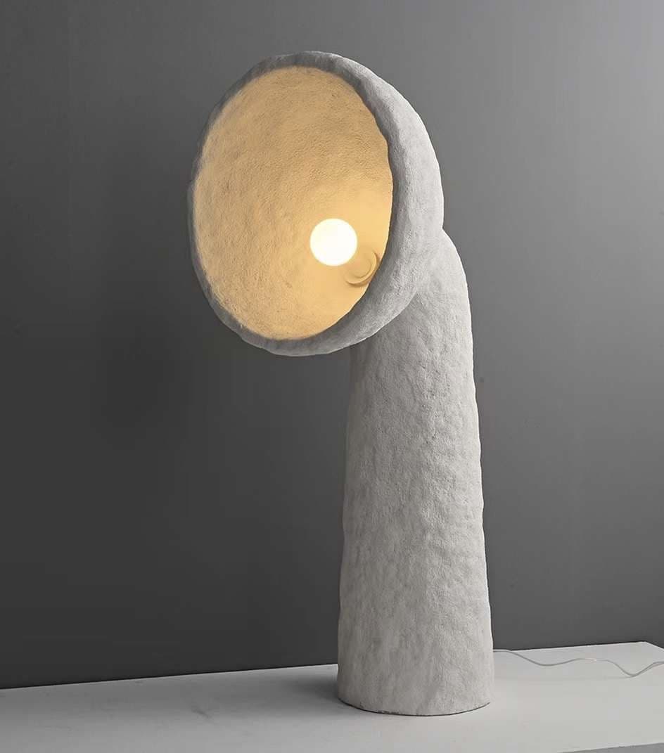 A floor lamp built around one dramatic gesture — a glowing disc balanced on a curved, sculptural stem.